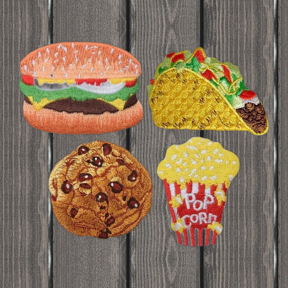 Four fast food embroidered patches: burger, popcorn, cookie and taco, on a wood background