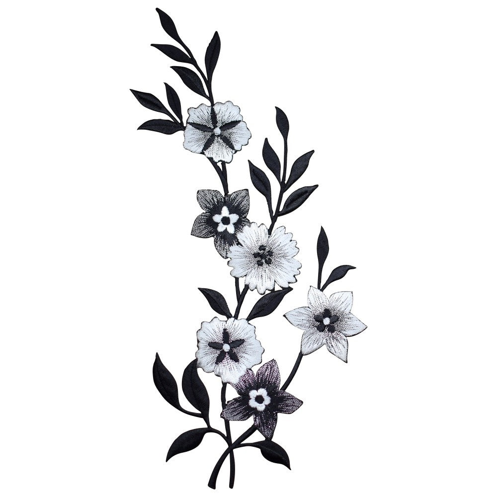 Embroidered appliqué featuring a winding vine of six flowers and several leaves, stitched in white, black, and grayscale thread, against a white background.