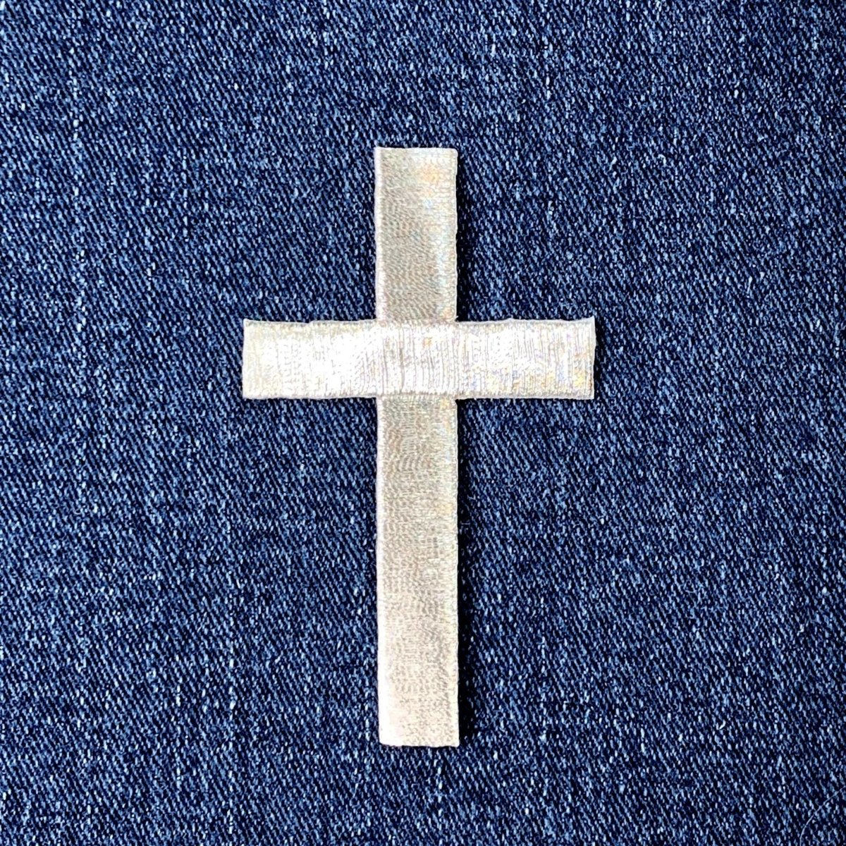 a silver cross patch on a denim background