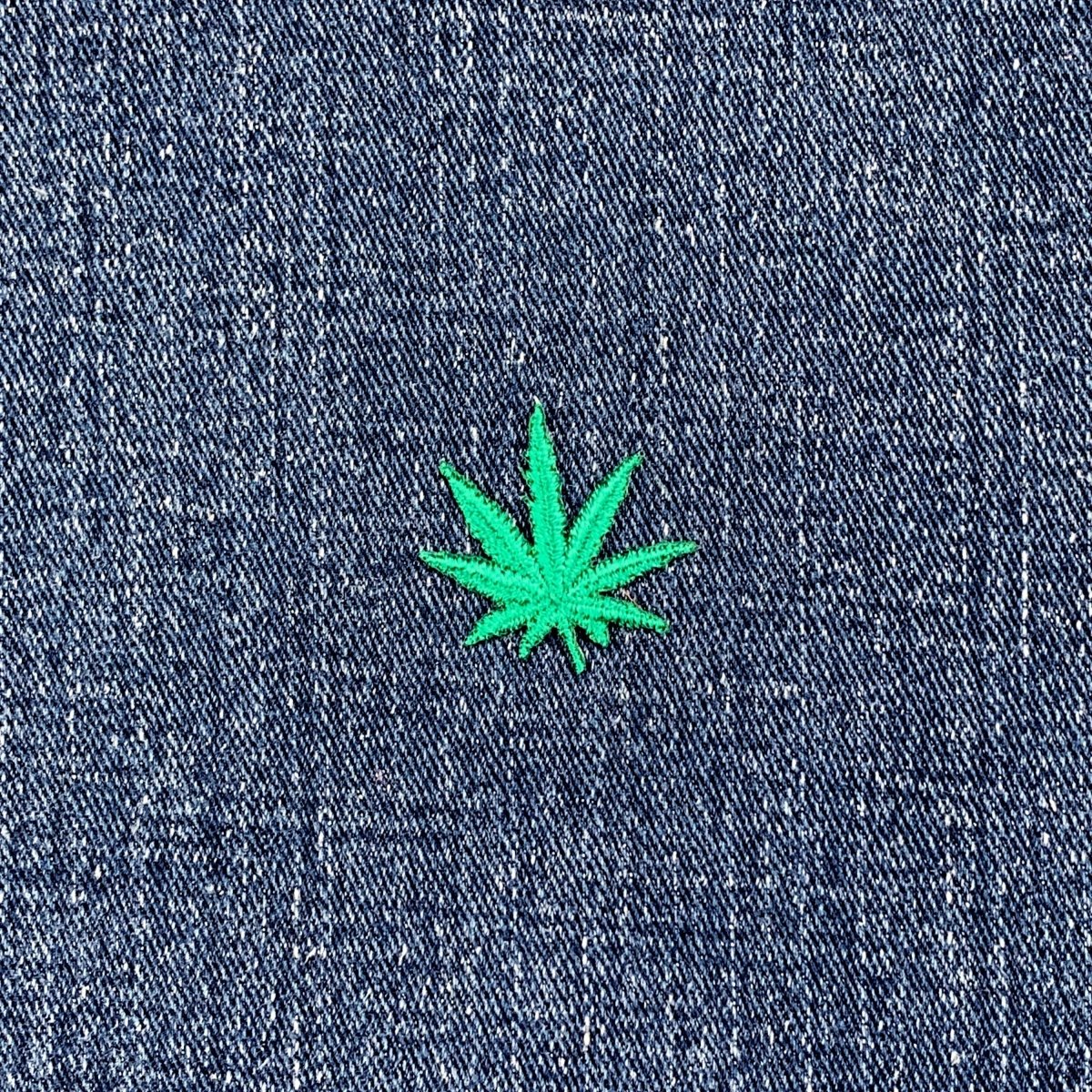 Green cannabis leaf patch on blue denim fabric