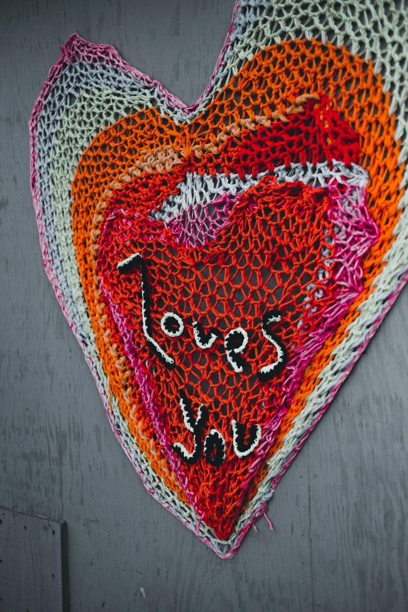 a crocheted heart hanging on a wall