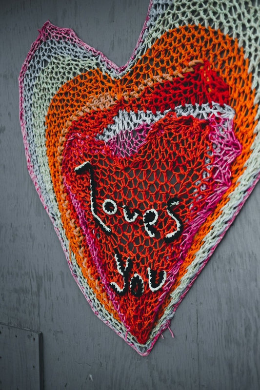 a crocheted heart hanging on a wall