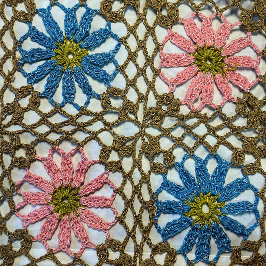 a close up of a crocheted doily with flowers on it