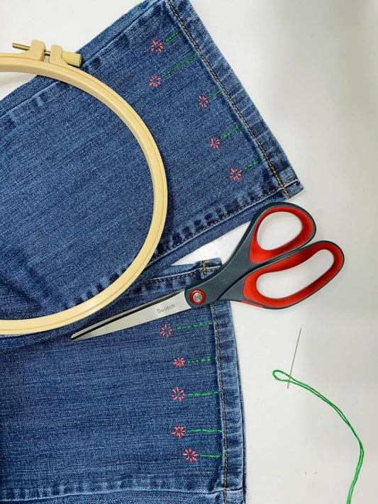 a pair of scissors sitting on top of a pair of jeans