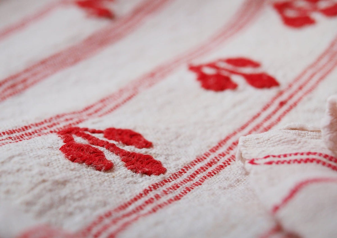 a white teddy bear laying on a red and white blanket