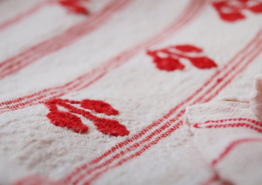 a white teddy bear laying on a red and white blanket