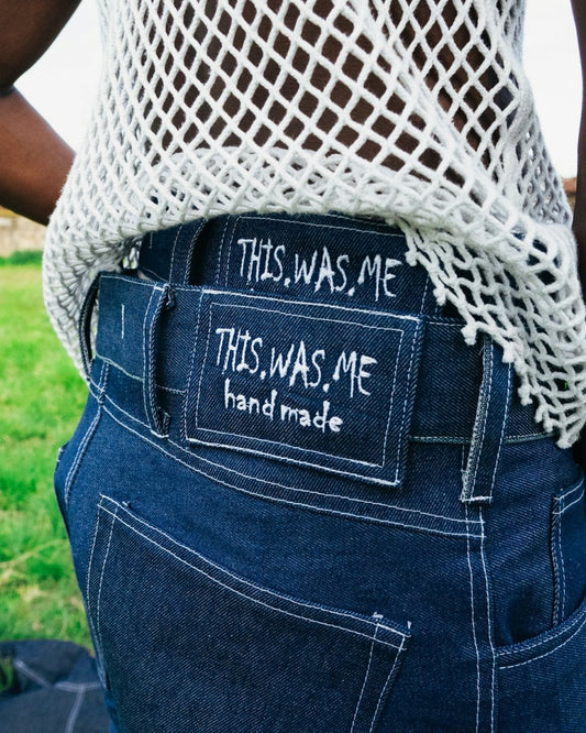 Person wearing dark denim jeans with embroidered label.