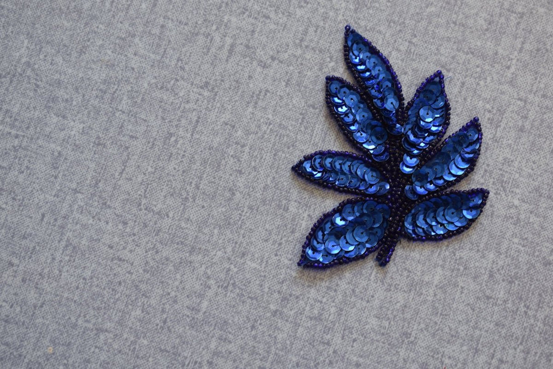 A blue sequined leaf applique on gray fabric
