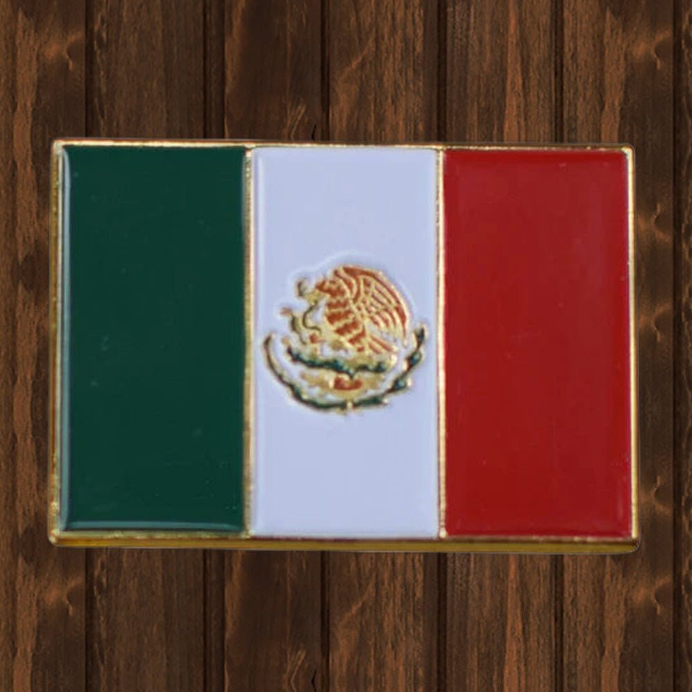 Mexican flag enamel lapel pin with green, white and red stripes on a wood background