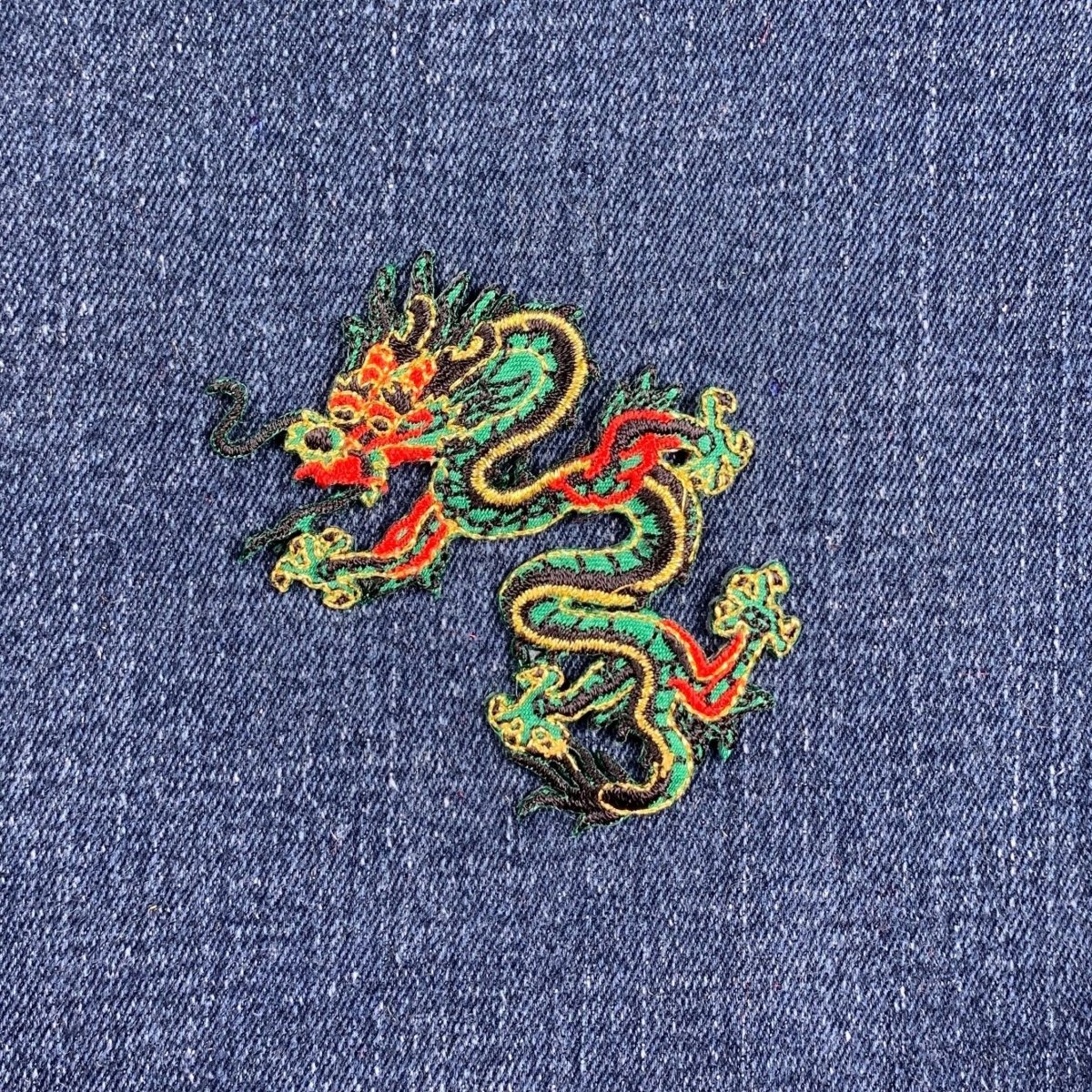 Embroidered dragon patch on denim fabric