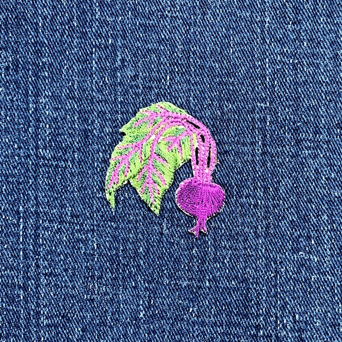 Embroidered purple and green beet patch on blue denim fabric