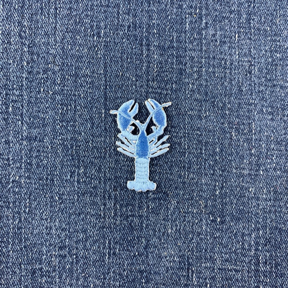 Light blue embroidered crawfish or lobster patch, 1.5 inches, on denim.