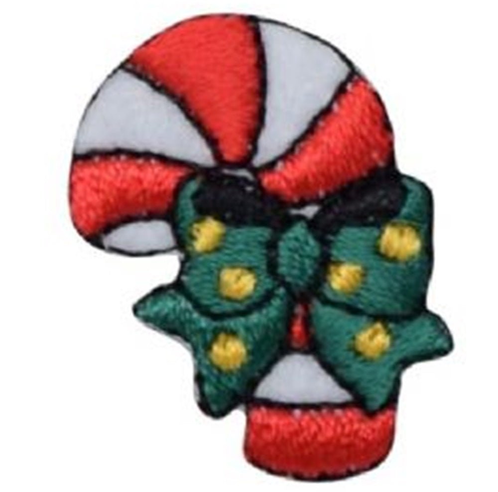 A small embroidered appliqué patch shaped like a candy cane with red and white diagonal stripes. A green bow with yellow polka dots is tied around the middle of the cane.