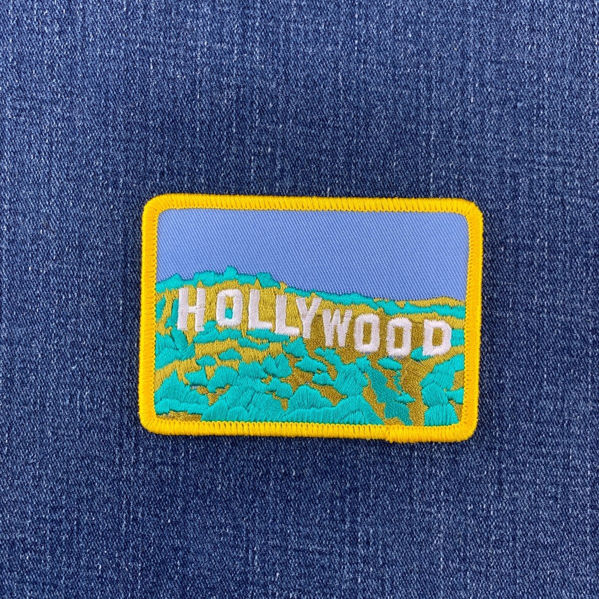 Embroidered patch with 'Hollywood' text on a blue denim background