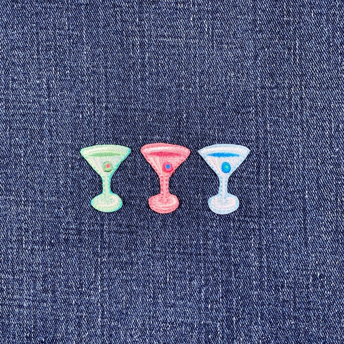 three embroidered martini patches in green, blue, and pink displayed on a denim fabric