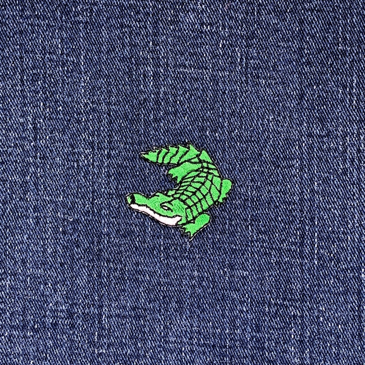 Green alligator patch on blue denim fabric
