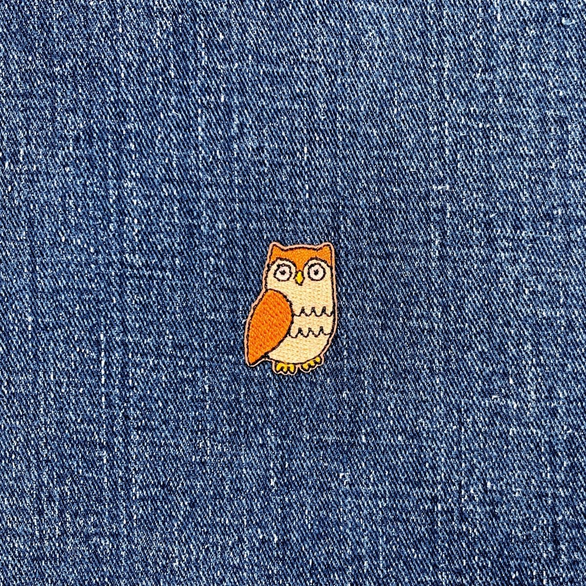Small owl patch on a denim fabric background
