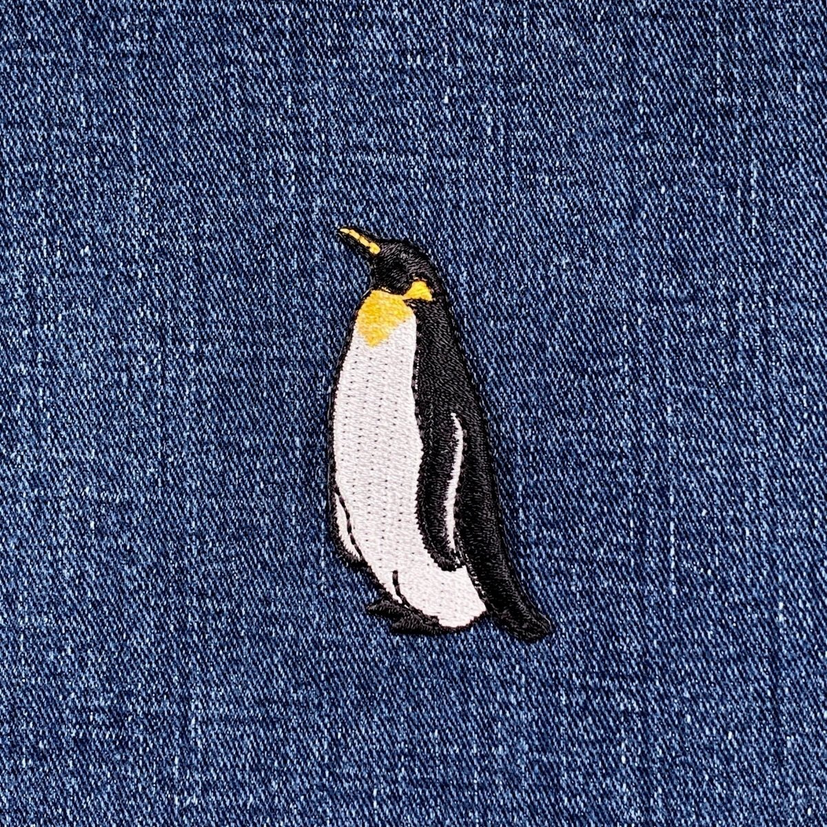 Embroidered penguin patch on denim fabric