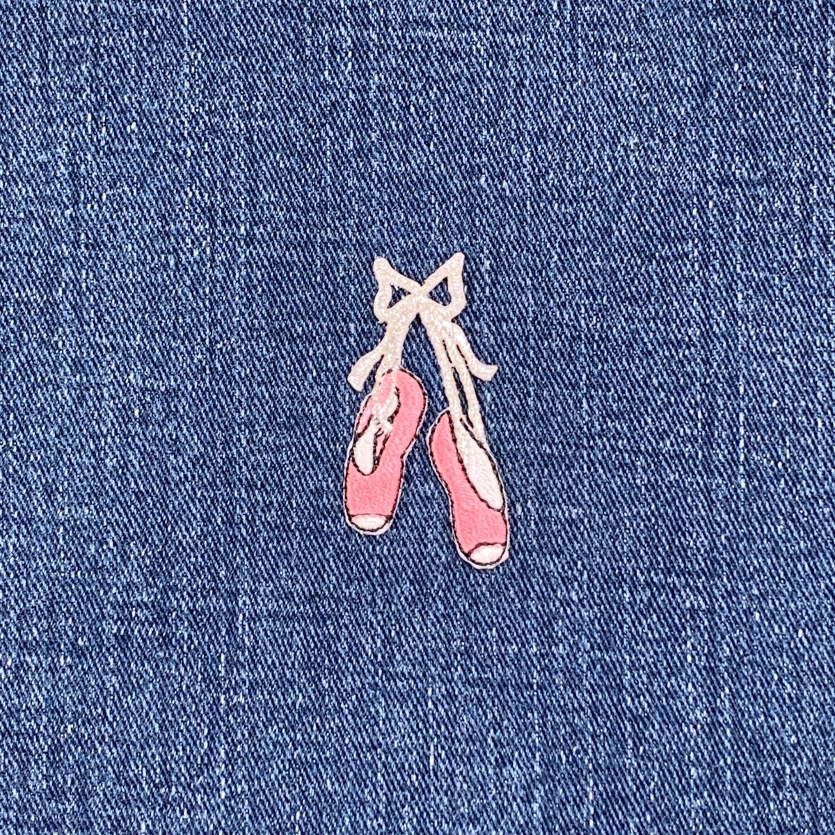 Embroidered pink ballet shoes patch on blue denim fabric