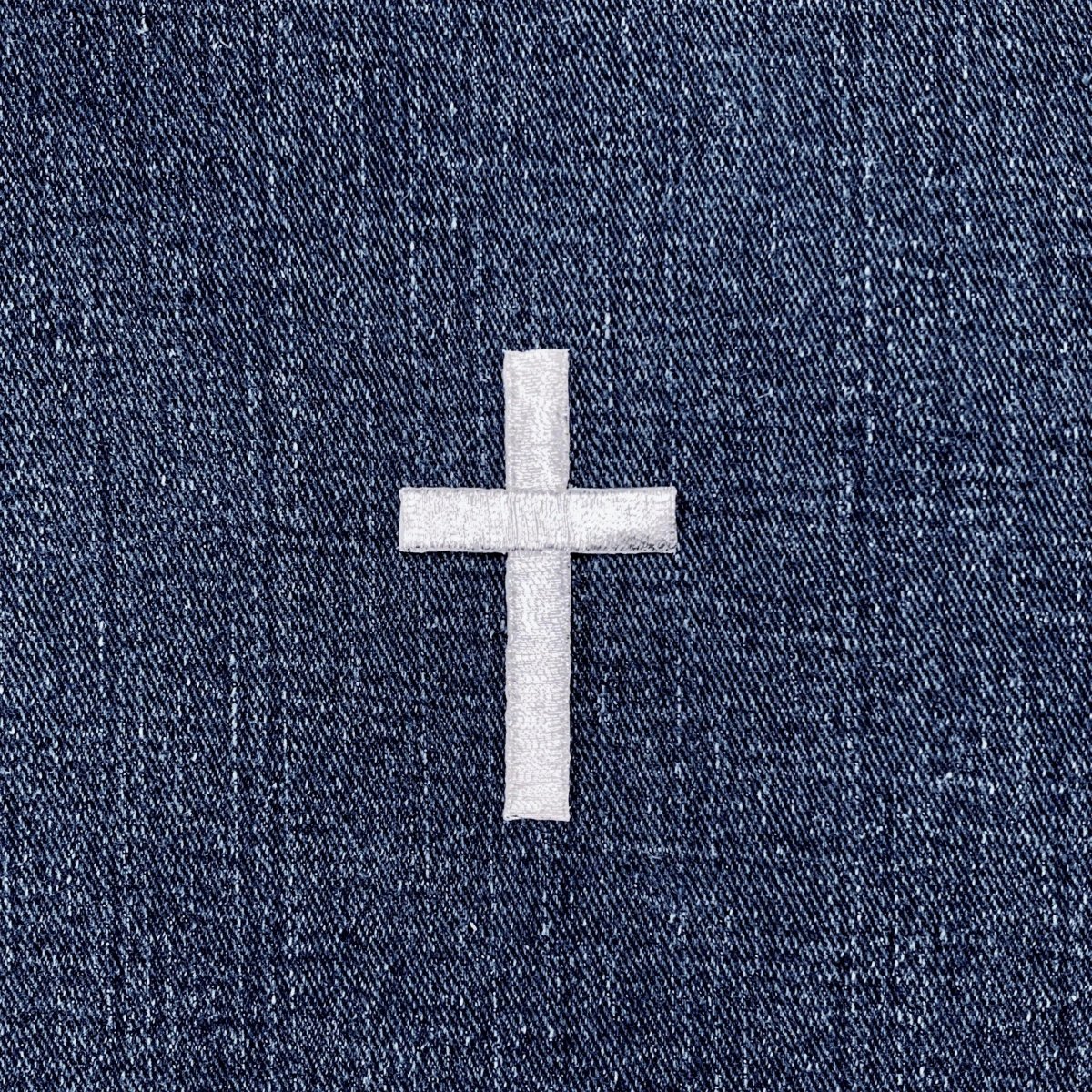 Silver cross patch on a blue denim background
