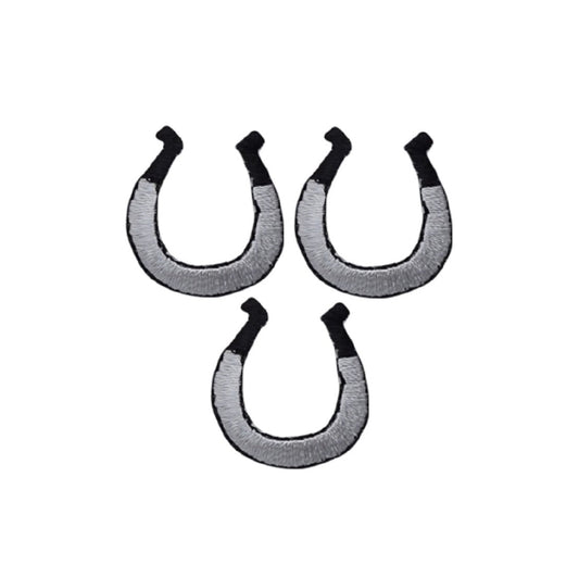 three silver and black horseshoe patches on a denim background
