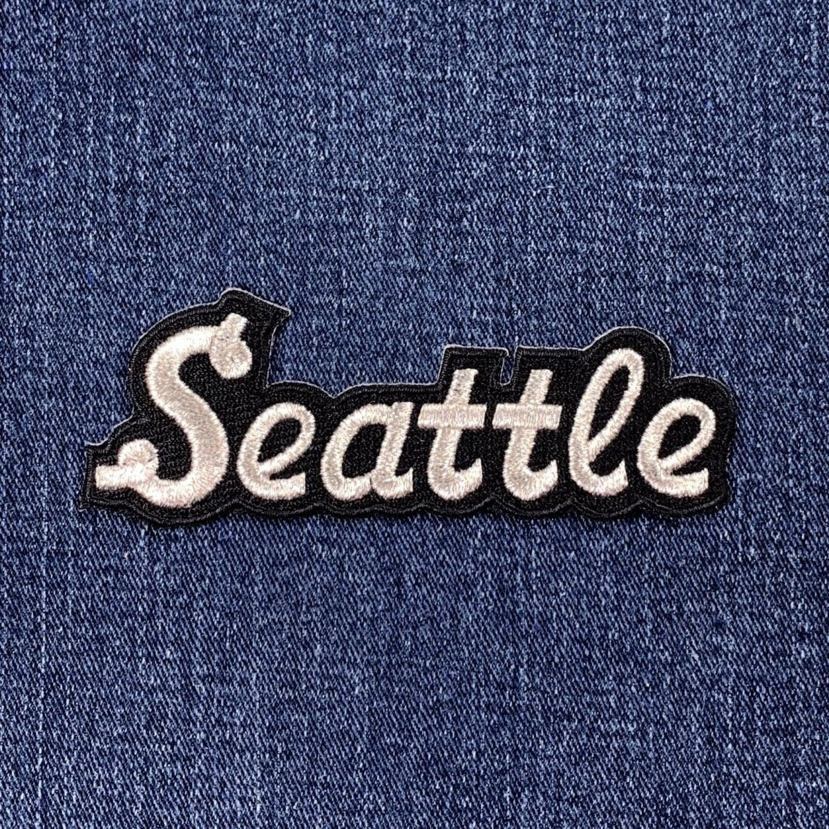 Embroidered patch with 'Seattle' text on denim fabric