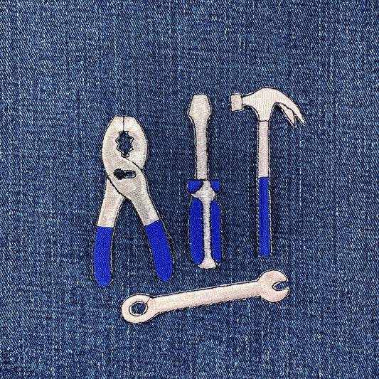 Set of tool patches including pliers, screwdriver, hammer, and wrench on a denim background