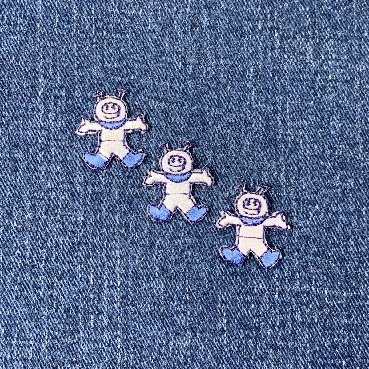 Three astronaut patches on a denim background