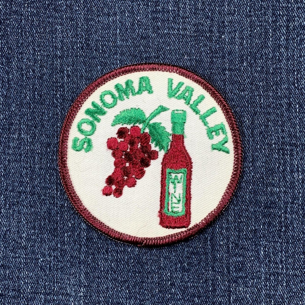 A circular embroidered patch featuring a cluster of dark red grapes and a bottle of red wine against a white background. The words 'SONOMA VALLEY' are stitched in green text around the top curve, displayed on a denim background.