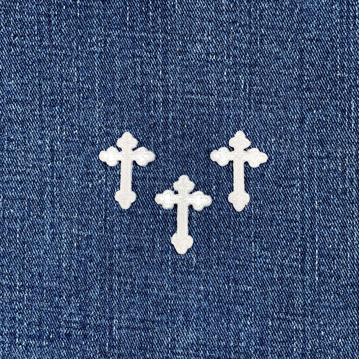 3 White cross-shaped patches on a blue denim background